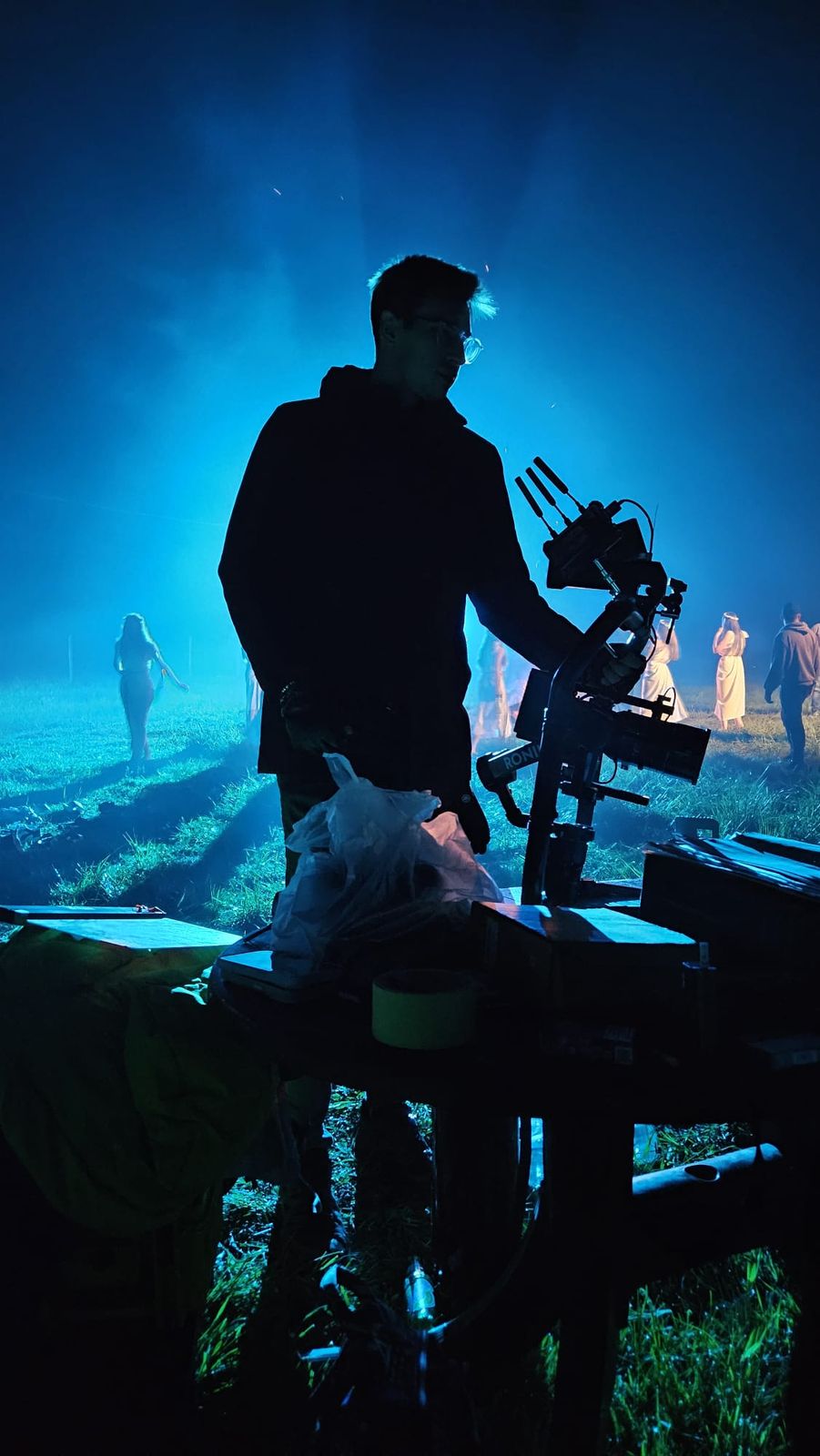 Silhouette of Matei with a camera on a gimbal, on a film set in blue haze