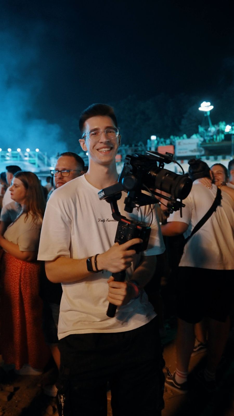 Matei smiling with his camera on a gimbal at a festival at night